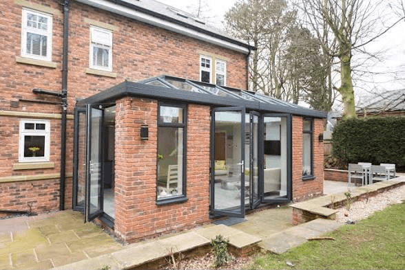 Modern orangery extension with grey aluminium bifold doors and glass roof on a red brick home